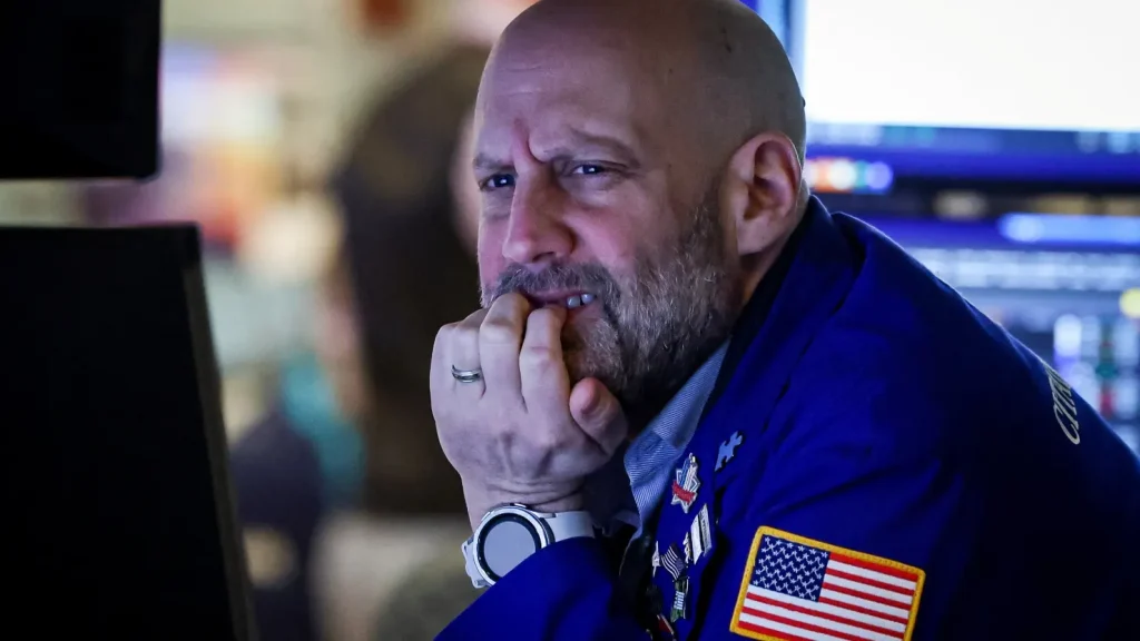 Professional traders monitoring the New York Stock Exchange floor during a period of high market volatility and falling indices.