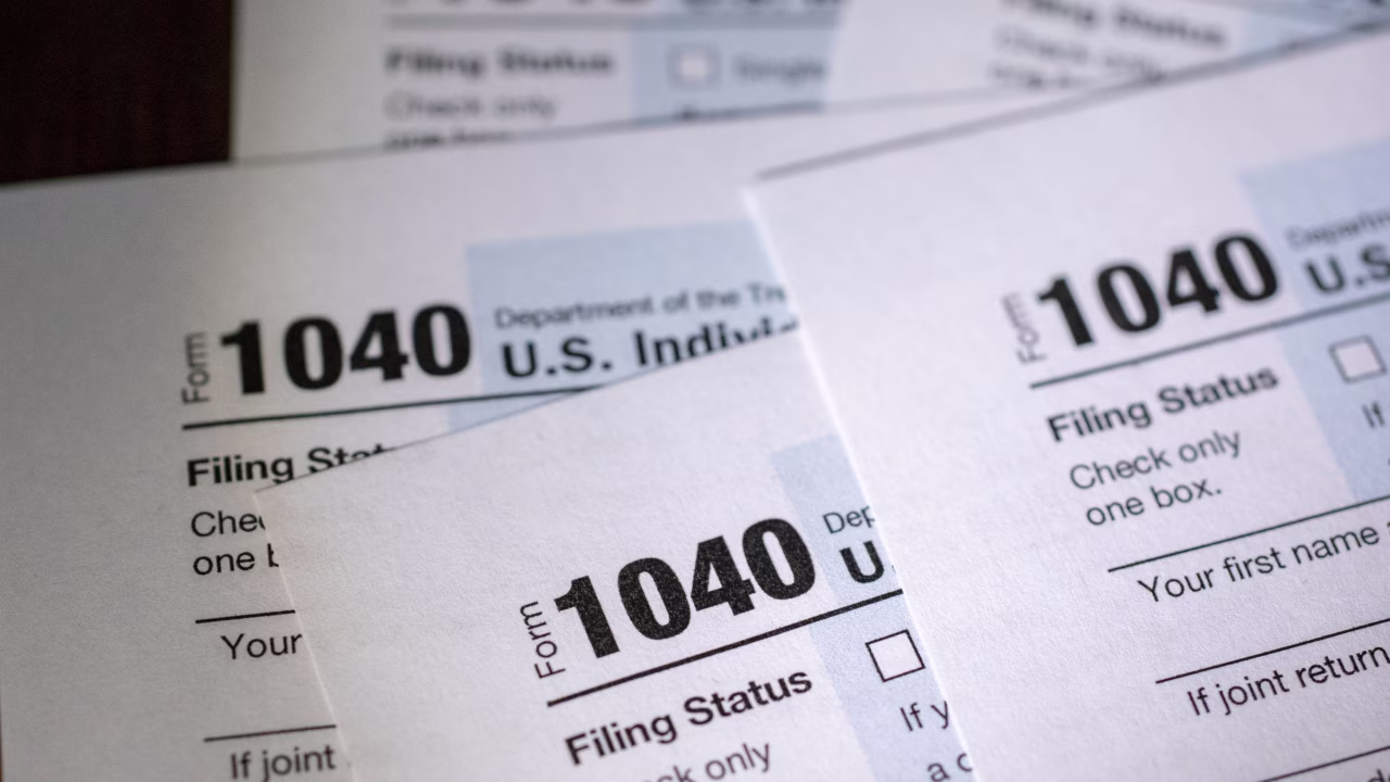 A person reviewing tax documents on a laptop with a calendar showing April 15, 2026.