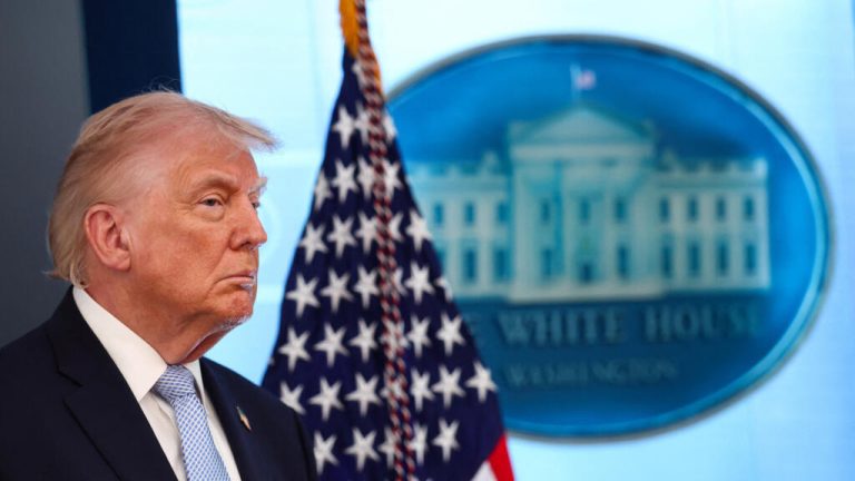 A cargo ship passing through the Strait of Hormuz under a clear sky, representing the reopening of the waterway.